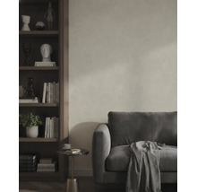 Woonkamer met grijze bank, gestructureerde wandafwerking, houten boekenkast en bijzettafel.