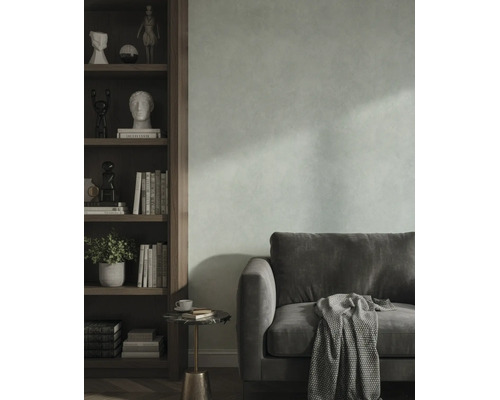 Woonkamer met gestructureerde wand, fluwelen bank en een houten boekenkast met decoratieve voorwerpen.