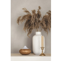 Witte geribbelde keramische vaas met gedroogd pampasgras, een aroma diffuser met houtlook en een gouden kandelaar op een plank.