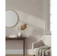 Licht ingerichte woonkamer met beige muurverf, ronde spiegel, houten consoletafel en comfortabele fauteuil.