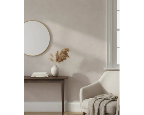 Licht ingerichte woonkamer met beige muurverf, ronde spiegel, houten consoletafel en comfortabele fauteuil.