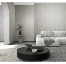 Moderne woonkamer met behang met textuur, bank, ronde salontafel en stenen vloer. Licht en georganiseerd.