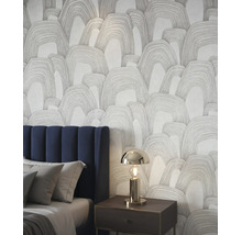 Vliesbehang met abstract boogpatroon in een moderne slaapkamer naast een bed met blauw hoofdbord.