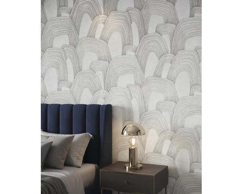 Vliesbehang met abstract boogpatroon in een moderne slaapkamer naast een bed met blauw hoofdbord.