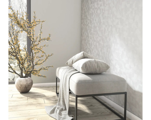 Licht interieur met een gestoffeerde zitbank, gestreepte kussens, een plaid, geometrisch behang en een decoratieve kunstplant.