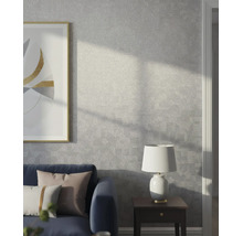 Moderne woonkamer met grijs structuurbehang met een subtiel geometrisch patroon, een blauwe bank, bijzetttafel en lamp.