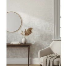 Vliesbehang met subtiel geometrisch patroon in een lichte, modern ingerichte woonkamer met houten tafel, spiegel en fauteuil.