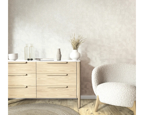 Lichte woonruimte met behang met structuur, een moderne houten ladekast en een zachte fauteuil op een lichte parketvloer.