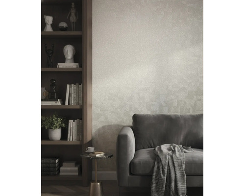 Gestructureerd vliesbehang in een moderne woonkamer achter een grijze bank en naast een donkere houten boekenkast.