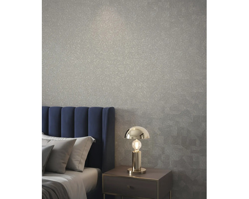 Slaapkamer met structuurbehang, blauw gestoffeerd hoofdbord en moderne metalen tafellamp op een nachtkastje.