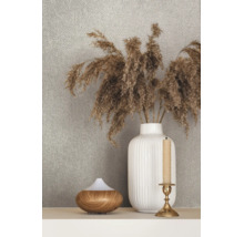 Behang met structuur achter een decoratieve scène met een geribbelde vaas met droogbloemen, een diffuser in houtlook en een kandelaar.