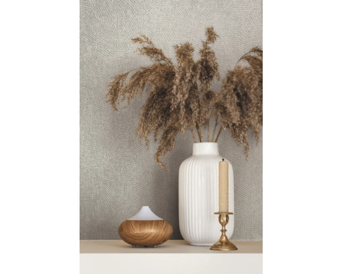 Behang met structuur achter een decoratieve scène met een geribbelde vaas met droogbloemen, een diffuser in houtlook en een kandelaar.