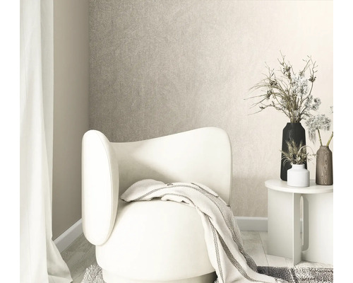 Licht ingerichte woonkamer met gestructureerd vliesbehang, een moderne fauteuil, bijzettafel en vazen met droogbloemen.