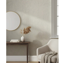 Gestructureerd vliesbehang met een fijn visgraatmotief in een lichte woonkamer met consoletafel, spiegel en fauteuil.