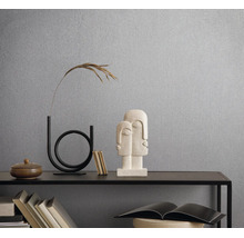 Gestructureerd vliesbehang op een wand achter een moderne sidetable met decoratie en sculpturen in een lichte, georganiseerde kamer.