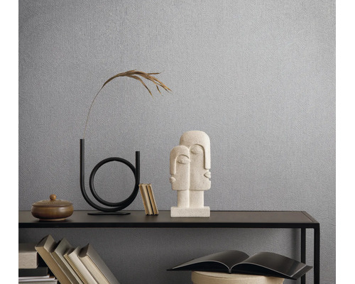 Gestructureerd vliesbehang op een wand achter een moderne sidetable met decoratie en sculpturen in een lichte, georganiseerde kamer.