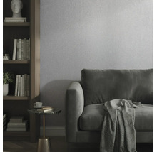 Moderne woonkamer met gestructureerd behang, fluwelen bank en houten boekenkast.