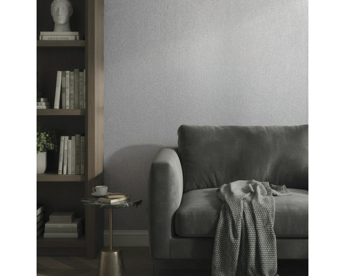 Moderne woonkamer met gestructureerd behang, fluwelen bank en houten boekenkast.