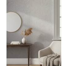 Gestructureerd vliesbehang in een lichte woonkamer met een ronde spiegel, houten consoletafel en een comfortabele fauteuil.