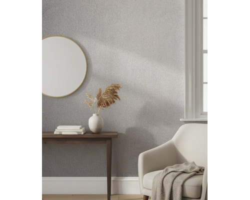 Gestructureerd vliesbehang in een lichte woonkamer met een ronde spiegel, houten consoletafel en een comfortabele fauteuil.