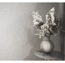 Behang met textuur in een modern ingerichte kamer met een vaas op een ronde bijzettafel.