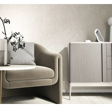 Moderne lichte woonkamer met gestructureerd vliesbehang op de muur, een fauteuil met gestreept kussen en een houten dressoir.