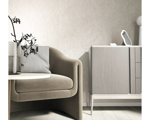 Moderne lichte woonkamer met gestructureerd vliesbehang op de muur, een fauteuil met gestreept kussen en een houten dressoir.