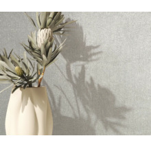 Gestructureerd behang met een fijn lijntjespatroon op een muur naast een vaas met bloemen.