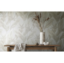 Behang met groot bladmotief in lichte tinten achter een houten bank met decoratie.
