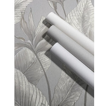 Drie rollen behang met textuur op behang met een groot tropisch bladerpatroon.