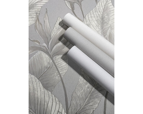 Drie rollen behang met textuur op behang met een groot tropisch bladerpatroon.