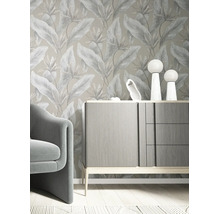 Vliesbehang met botanisch bladpatroon in een modern ingerichte kamer met grijs dressoir en fauteuil.
