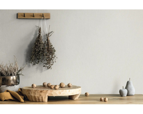 Licht gestructureerde wand met rustieke decoratie, houten plank, walnoten, gedroogde kruiden en stenen vruchten op een houten tafel.