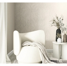 Licht ingerichte woonkamer met gestructureerd vliesbehang, een moderne fauteuil, bijzettafel en vazen met droogbloemen.