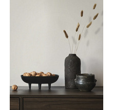 Dressoir van donker hout met een decoratieve zwarte schaal op drie poten gevuld met walnoten, een vaas met droogbloemen en een pot.