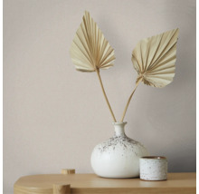 Minimalistische decoratie met een gespikkelde keramieken vaas, twee gedroogde palmbladeren en een bijpassend potje op een houten oppervlak.
