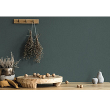 Donkergroen geverfde muur met rustieke decoratie van hout, gedroogde kruiden en walnoten op een houten tafel.