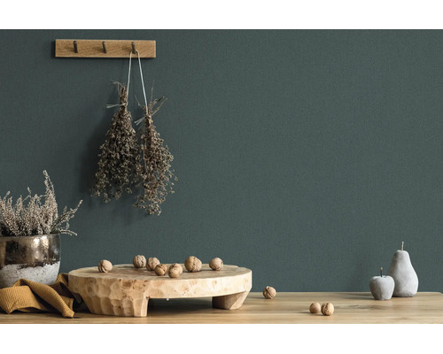 Donkergroen geverfde muur met rustieke decoratie van hout, gedroogde kruiden en walnoten op een houten tafel.