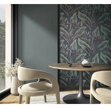 Vliesfotobehang met jungle-motief en tropische bladeren in een moderne eethoek met houten tafel en gebogen stoelen.