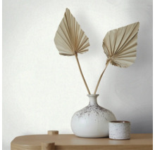Vliesbehang met fijne lengtestructuur achter een vaas met gedroogde palmbladeren op een houten tafel.