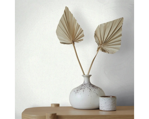Vliesbehang met fijne lengtestructuur achter een vaas met gedroogde palmbladeren op een houten tafel.