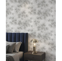 Gestructureerd behang met een floraal naaldpatroon in een slaapkamer met een gestoffeerd hoofdbord, kussens en een metalen nachtlampje.