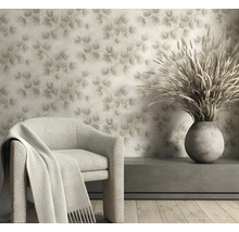 Vliesbehang met dennennaaldenpatroon in een lichte woonkamer met fauteuil en vaas met droogbloemen.