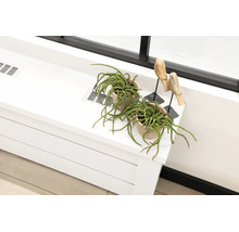 Kamerplanten in potten van klei en houten figuren op een plank met ventilatieroosters naast een raam.