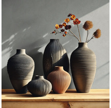Set van vijf verschillende keramische vazen met ribbelstructuur op een houten oppervlak, decoratieve vazen in aardetinten met droogbloemen.