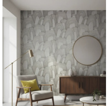 Vliesbehang met abstract boogpatroon in een moderne woonkamer met fauteuil, dressoir en ronde wandspiegel.