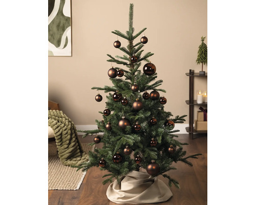 Versierde kerstboom in een lichte woonkamer met bruine kerstballen in verschillende maten, matte en glanzende afwerkingen.