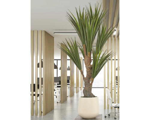 Kunstplant in een crèmekleurige pot in een licht, modern kantoor met houten lamellen scheidingswanden, bureaus en bureaustoelen.