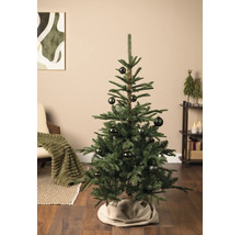 Een versierde kerstboom in een lichte woonkamer met houten vloer. De boom heeft kerstballen met patronen.