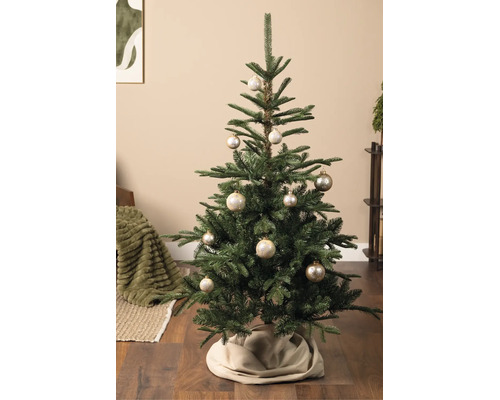Kerstboom gedecoreerd met champagnekleurige kerstballen met sneeuwvlokkenpatroon in een woonkamer.